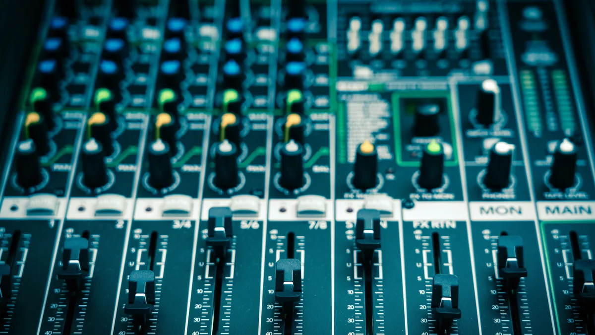 Audio mixing console with sliders and knobs